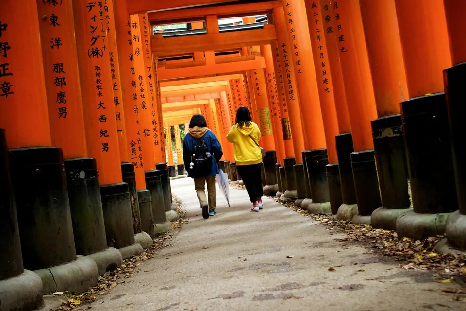Before: two visitors walking through the torii gates in Kyoto